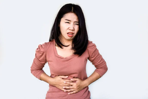 アジアの女性は胃の痛みの手から彼女のおなかを保持彼女の隔離されたグレーの背景 — ストック写真