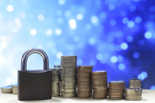 Coin money stack and lock, on blue light background. Saving and financial security concept.
