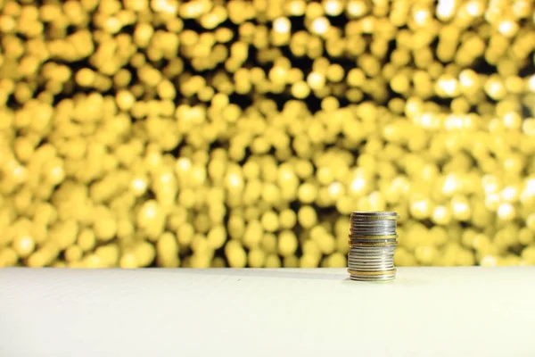 single column coin stack on yellow out of focus light background. For business saving and money related concept.