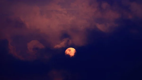 Orangefarbene Sonne steigt durch dunkelblaue und violette Morgenwolken — Stockfoto