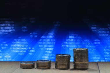 Güvenli internet ortamında büyüyen iş. Madeni para yığın grafiği şekli artan sütunlara yığılmış. Bilgisayar perde göstermek ile beyaz ikili sayı fotoğrafı.