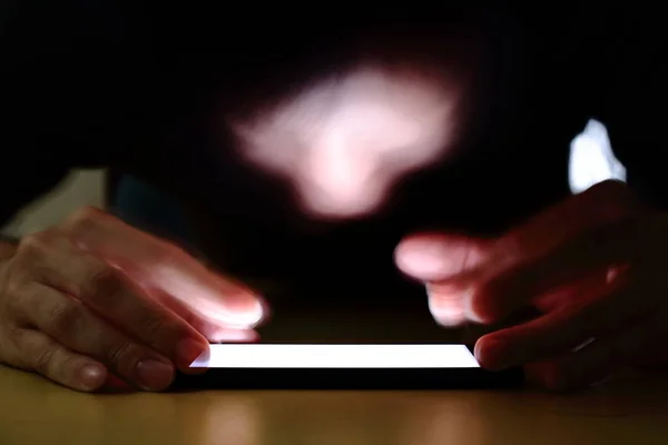 Smartphone bağımlılığı sosyal medya tuzak. Bir karanlık odada Smartphone basarak beyaz genç bir adam. uzun pozlama atış smartphone üzerinde duruldu. Modern toplumsal sorun kavramı.
