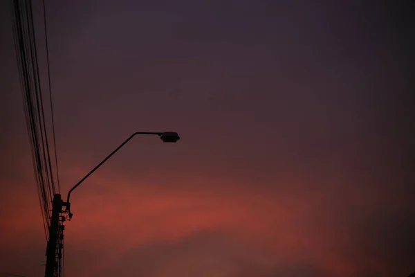ライトポールシルエットとレッドホットサンセットスカイ 錆色の雲の背景 産業シーンのコンセプト — ストック写真