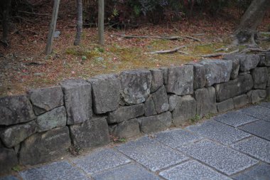 Taştan yapılmış istinat duvarını kes yeşil alanı ayır ve granit taş levhalar patikayı kes. peyzaj ve bahçe tasarımı detayları. 