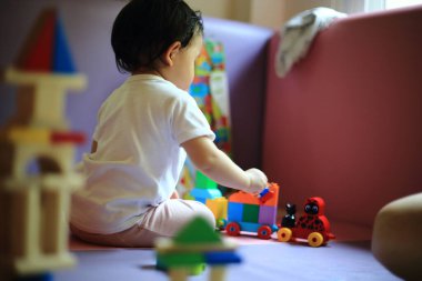 Oyuncak bebek, tahta bloklar şekil alıyor. Arka planda oynayan bulanık bebek. çocuk gelişimi ve oyun öğrenme kavramları.