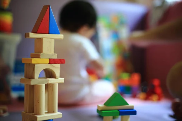 Oyuncak bebek, tahta bloklar şekil alıyor. Arka planda oynayan bulanık bebek. çocuk gelişimi ve oyun öğrenme kavramları.
