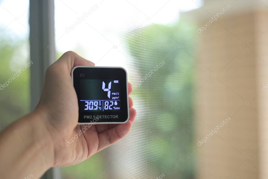 Air quality measurements. man hand holding handheld PM 2.5 small dust particles sensor. low particulate matter in the air indicated good healthy breathable air. livable cities with good environment.