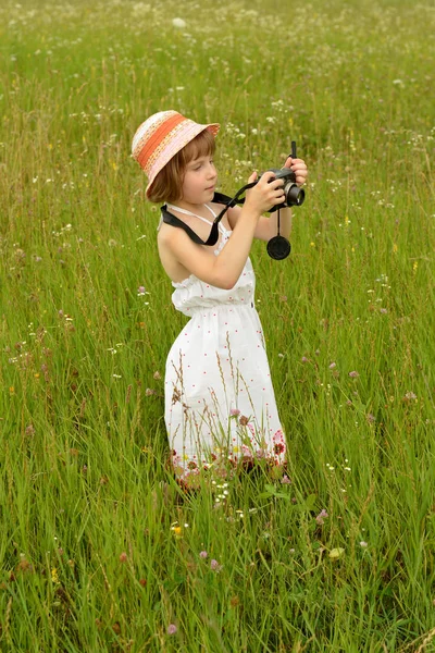 Fotógrafo de bebé (una niña) con una cámara en el fondo de la naturaleza —  Fotos de Stock