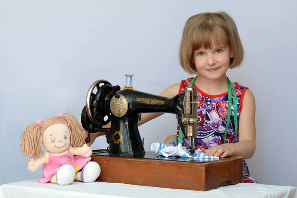 çocuk, çocuk,(little girl) terzi için eski dikiş makinesi üzerinde Bebek Giyim diker..