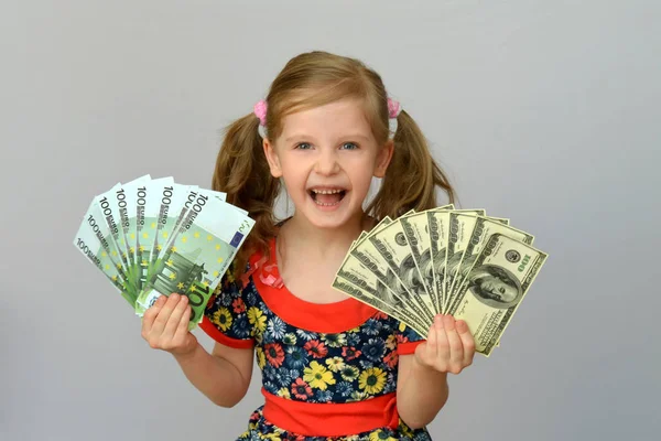 Malá holčička drží v ruce balíček dolarů a EUR. — Stock fotografie