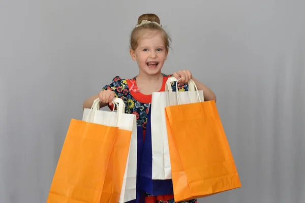 A menina, o comprador segura os sacos de compras coloridos . — Fotografia de Stock