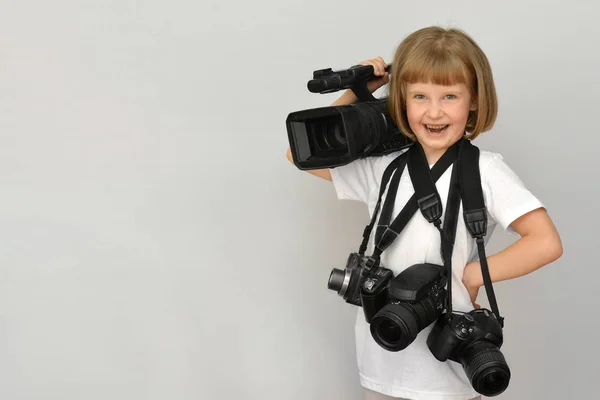 Roztomilá holčička (dítě, děcko) s fotoaparátem a kamerou je šťastný. Bílé pozadí s místem pro nápisy. — Stock fotografie