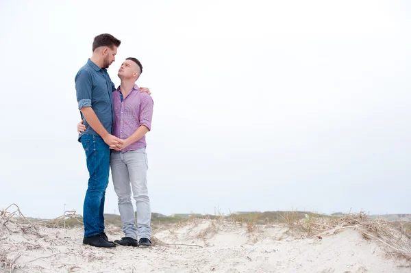 Gay män embracing på en strand — Stockfoto
