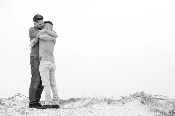 Gay män embracing på en strand — Stockfoto