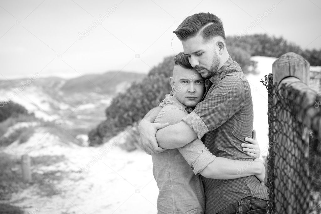 Gay men embracing on a fence