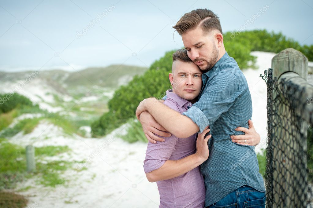 Gay men embracing on a fence