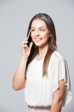 Gülümseyen bir telefon tutarak genç iş kadın portresi