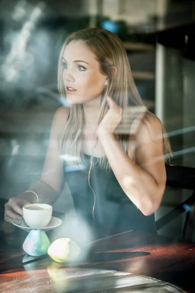 Meisje zat in het venster van een coffeeshop koffie drinken — Stockfoto