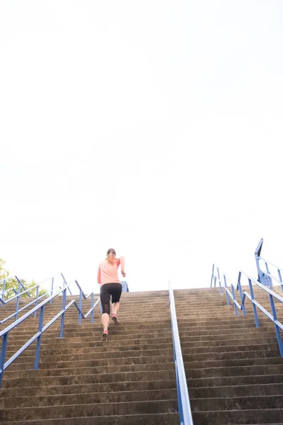 Atlética mujer corriendo por un tramo de escaleras — Foto de Stock