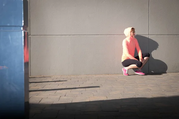 Atleta feminina que se estende na rua — Fotografia de Stock