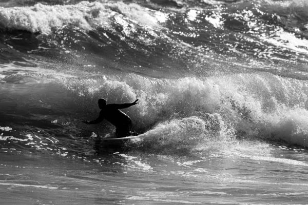 Sihouette des Surfers, der auf einer Welle reitet — Stockfoto