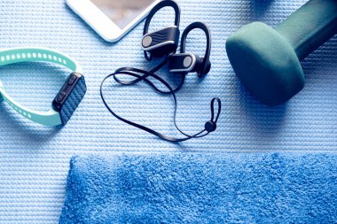 Mavi yoga minderinde spor aletleri ve elektronik eşyalar.