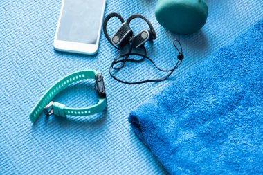 Mavi yoga minderinde spor aletleri ve elektronik eşyalar.