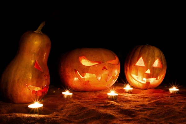 Tre Halloweenpumpor jack lampa i mörkret bland kan — Stockfoto