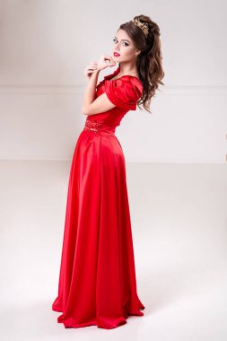 zarif kadın uzun Kırmızı elbiseli bir beyaz odada duruyor
