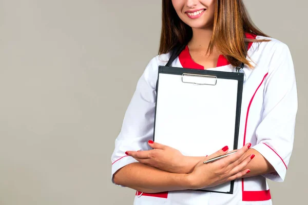 Mulher não identificada médico, enfermeira sorri segurando uma área de transferência, com lugar para texto — Fotografia de Stock