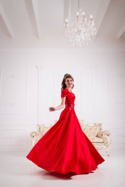 Zarif kadın uzun Kırmızı elbiseli elbise yanıp sönen bir beyaz odada duruyor