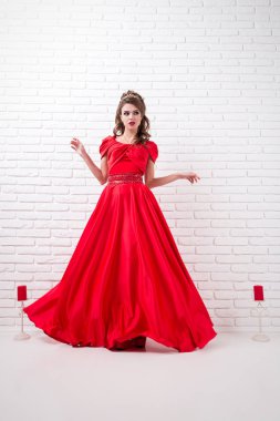 Zarif kadın uzun Kırmızı elbiseli elbise yanıp sönen bir beyaz odada duruyor