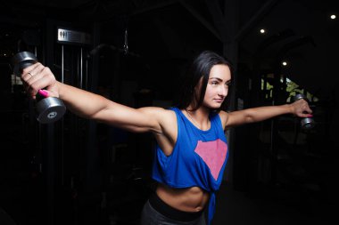 spor salonunda, ellerini iterek dumbbell asansörleri cinsel şişirilmiş rakam ile genç kız