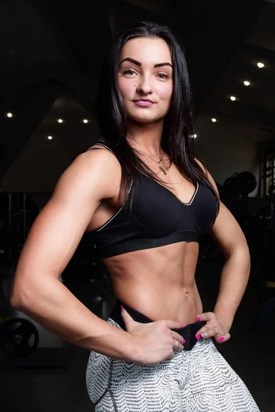 Ung flicka med sexuella uppblåsta figur, i gymmet, visar musklerna — Stockfoto