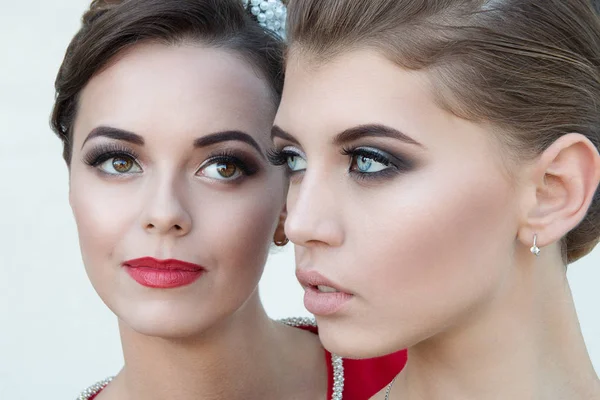 Due belle giovani donne con trucco di alta qualità, faccia da primo piano su uno sfondo leggero con un taglio di capelli professionale — Foto Stock