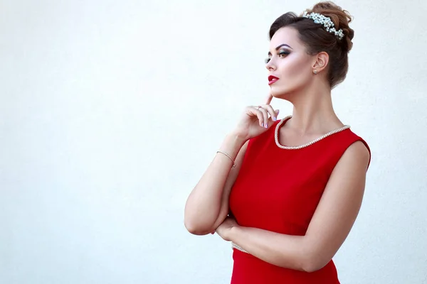 Hermosa joven en rojo con maquillaje de alta calidad, sobre un fondo claro con un corte de pelo profesional con espacio para el texto — Foto de Stock