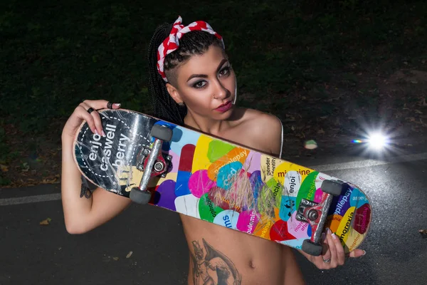 Стильна і сексуальна дівчина покриває свої голі цицьки використовуючи скейтборд — стокове фото
