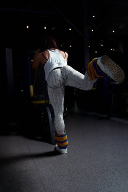 spor salonunda, cinsel şişirilmiş rakam ile genç kız ayaklarıyla ağırlık kaldırma kalça yoluna