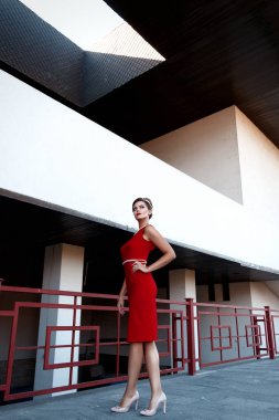 bir arka plan metin için yer ile geometrik binaların ayakta bir kısa Kırmızı elbiseli, güzel bir makyaj ile güzel genç kız