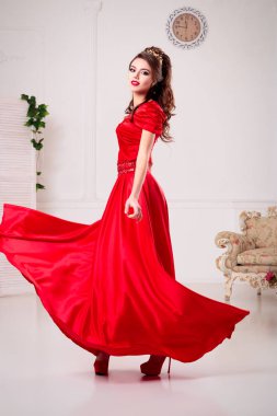 Zarif kadın uzun Kırmızı elbiseli bir beyaz odada şık, girdap elbise duruyor