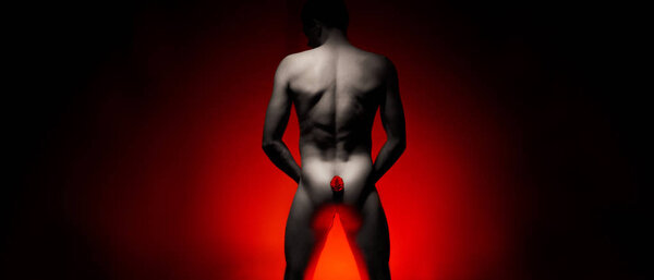 naked man with a rose between his buttocks on a background of red black gradient with space for text