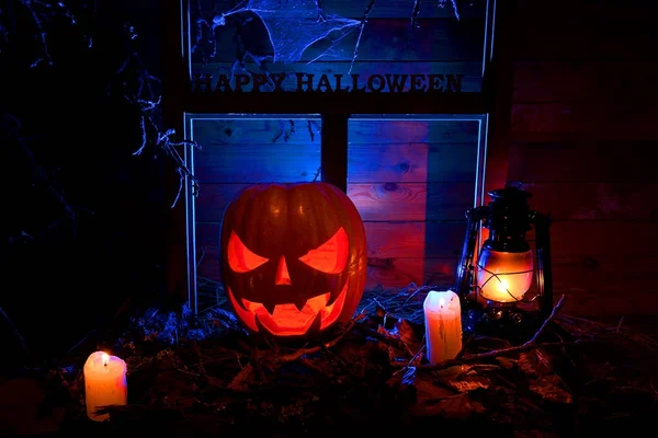 Halloween - calabazas, velas y una lámpara en hojas y troncos con —  Fotos de Stock
