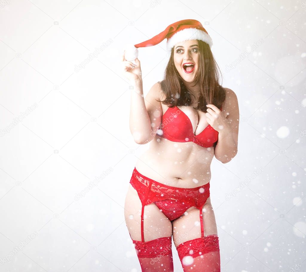 Happy cute fat Santa girl. Model in red lingerie and Santa hat. 