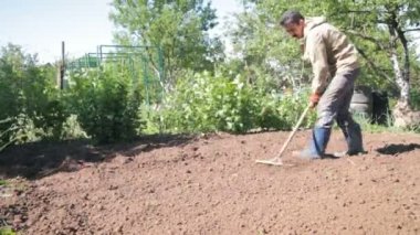 Bir çiftçi bir banliyö bölgesi, bir Bahçe, bir komisyon, yardımı ile lastik Çizmeli bitkiler ekime hazırlanması zemin tesviye bir adamdır.