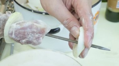 Bir adam bir yay ile bir şiş üzerinde et, piknik üzerinde video görüntüleri turşusu parçaları koyar. Barbekü