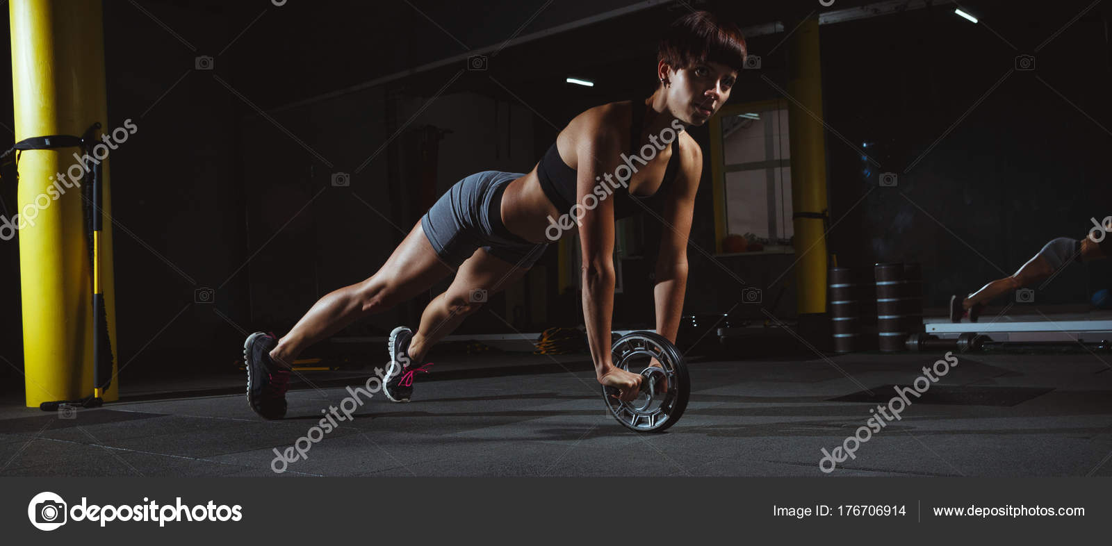 Fitness pige gør crossfit øvelser i fitnesscenter med hjul i mørke —  Stock-foto © TavRox #176706914
