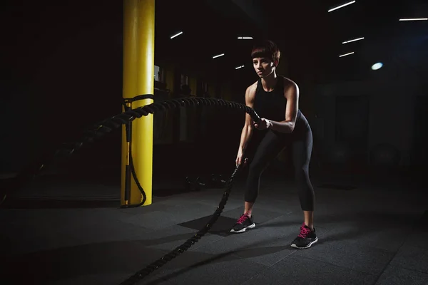 Fitness-Mädchen macht Crossfit-Übungen in Turnhalle mit großem Seil in da — Stockfoto