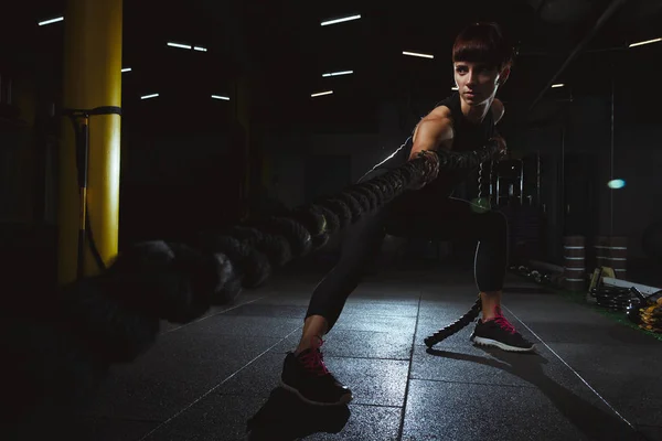 Fitness girl facendo esercizi di crossfit in palestra con grande corda in da — Foto Stock