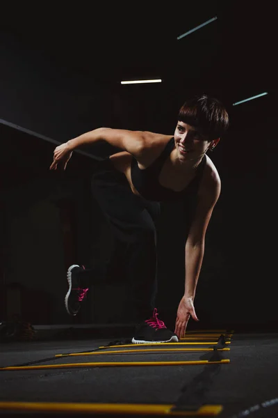 Fitness lány tornateremben sötét teremben, sport a crossfit gyakorolja — Stock Fotó