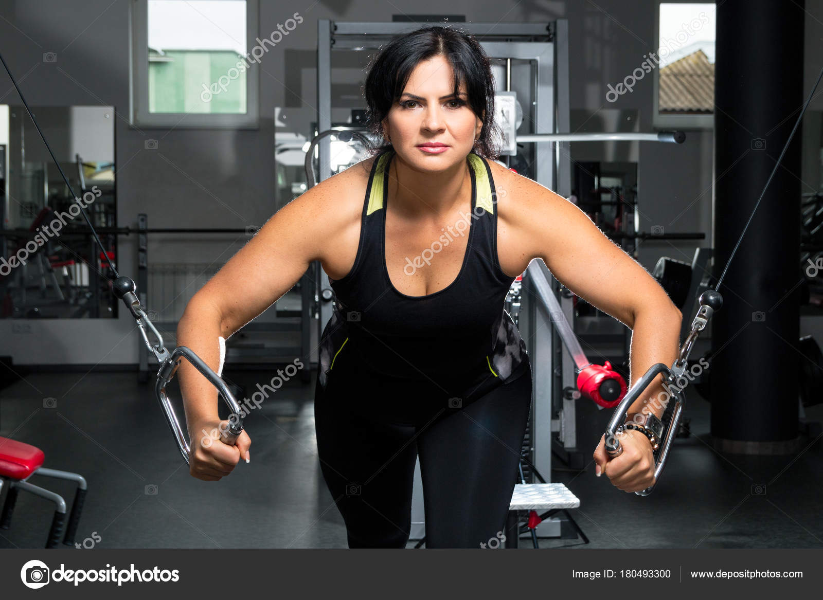 Woman plus size in gym doing exercises with training apparatus